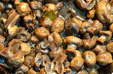 Fried mushrooms champignons with bay leaf in a pan.
