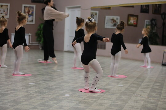 A group of ballet dancers kids in the gym doing exercises with a teacher