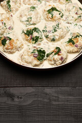 Delicious small meatballs with spinach in a creamy sauce in the frying pan