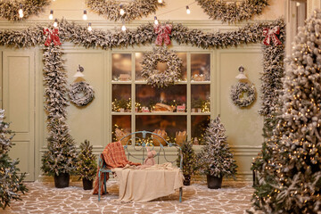 The snow-covered house is decorated for the new year. Vintage winter courtyard, decorated with Christmas trees, lanterns and a cozy bench and shop window with fresh pastries. Soft selective focus.