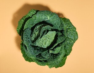 Cabbage intense green color with voluminous textured juicy leaves on pastel beige background. Concept proper nutrition and natural beauty.