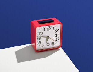 Vintage clock square shape and red color stand on white table. Idea of work, punctuality and...