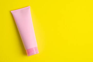 Empty a cosmetic pink tube of cream on green background with empty space.