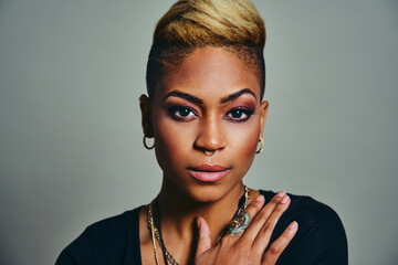 Portrait of a young cool woman with big silver ring and trendy jewelry Against Gray Background