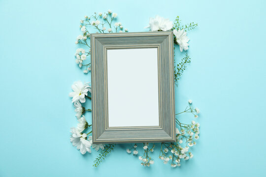 Blank photo frame with flowers on blue background