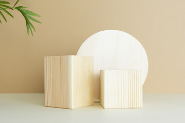 Wooden podiums, pedestals on a beige background with palm leaves. Showcases for the promotion of products, beauty, natural cosmetics. Abstract minimalistic elegant studio stage.