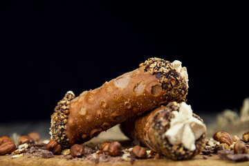 Cannoli, deep fried Italian delicious pastry tubes with a sweet ricotta cheese, chocolate chips and hazelnuts served on a wooden board