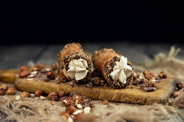 Cannoli, deep fried Italian pastry tubes with a sweet ricotta cheese, chocolate chips and hazelnuts served on a wooden board