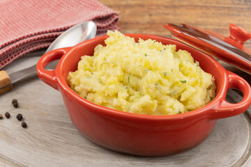 red casserole with creamy mashed potatoes on wooden table
