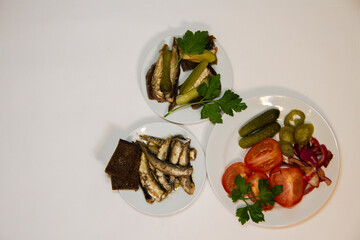 Still-life. Smoked sardines on toasted bread, pickled cucumbers and tomatoes