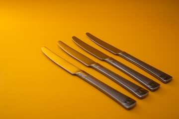 Knives made of metal, silver, lie on a yellow background