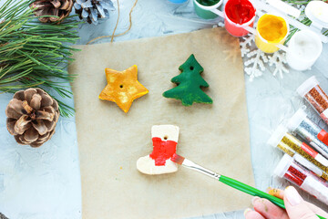 a brush with red paint paints a Christmas sock, DIY toys for the New Year, creative decoration for a Christmas tree made of salt dough