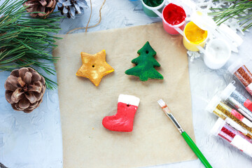 a brush with red paint paints a Christmas sock, DIY toys for the New Year, creative decoration for a Christmas tree made of salt dough