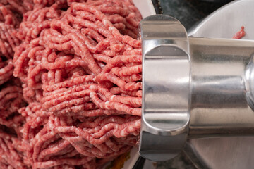 Minced meat coming out from modern electric grinder. Healthy fresh homemade minced meat. Selective...