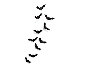 Halloween concept: A flock of black paper bats taking off on white background. Top view, flat lay, copy space.