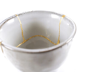 kintsugi gold cracks restoration, Japanese bowl fixed with the antique kintsukuroi restoration technique, the beauty of imperfections, representation of a trauma
