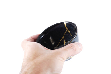 kintsugi gold cracks restoration, Japanese black bowl fixed with the antique kintsukuroi...