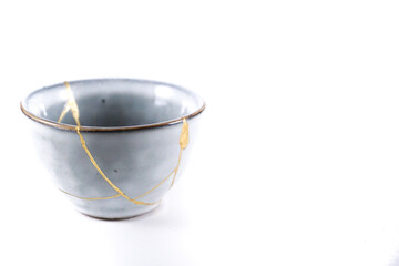 Isolated Japanese kintsugi bowl, antique pottery restored with gold cracks. Traditional gold fixing...