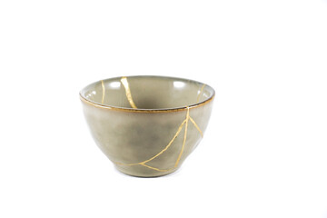 Isolated Japanese kintsugi bowl, antique pottery restored with gold cracks. Traditional gold fixing method.