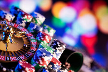 Casino theme.  Roulette wheel and poker chips on  colorful bokeh background.