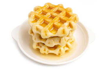 A Pile of Freshly Baked Round Butter Waffles, Belgian breakfast pastry dessert, topping with honey isolated on white background. Clipping path.