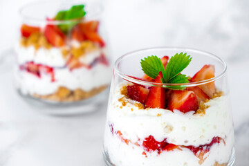 Strawberry trifle dessert with custard, cake crumb and fresh strawberry in glass on marble. Recipe of simple layered dessert with fresh berry and jam. Lactose free vegan dessert parfait.