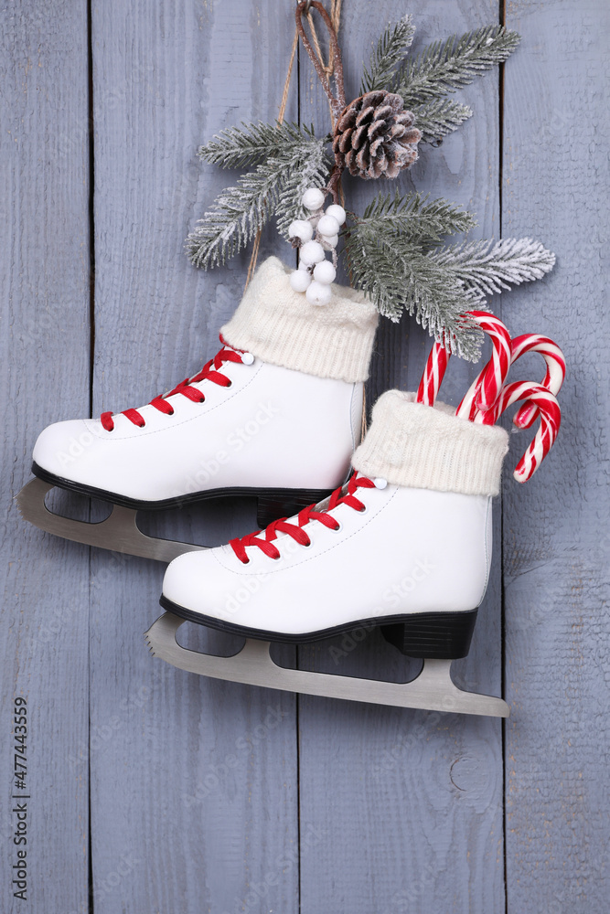 Wall mural Pair of ice skates with Christmas decor hanging on grey wooden wall