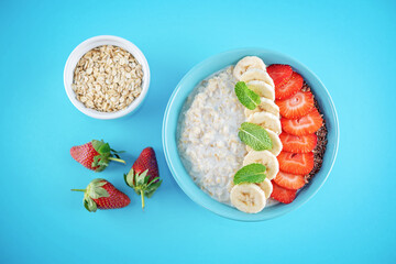 Oatmeal porridge with milk and fresh strawberries and banana slices in a bowl