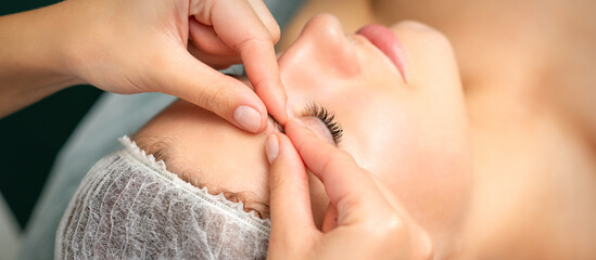 Manual sculpting face massage in the spa. Fingers of beautician make facial massage eyebrow of a...
