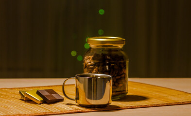 A glass jar with coffee beans and a cup on the table