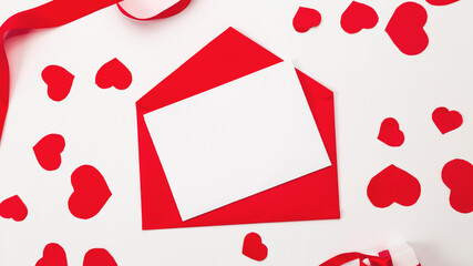 Red envelope with empty white card and paper hearts on white background. top view valentines day concept.