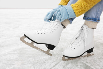 Woman lacing figure skates on ice rink, closeup