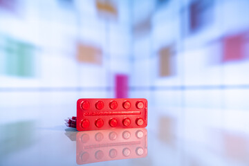 Colorful tablets with capsules and pills on mirror surface and blurred background