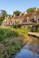Evening light falling on Arlington Row, late 14th century weavers cottages in the Cotswold village of Bibury, Gloucestershire UK