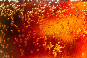 macro cola,Detail of Cold Bubbly Carbonated Soft Drink with Ice,Close up view of the ice cubes in dark cola background. Texture of cooling sweet summer's drink with foam and macro bubbles on the glass