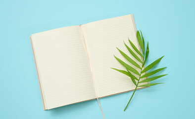 open notebook with blank white sheets on a blue background, top view.