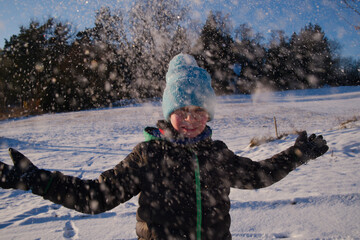 młody chłopak bawi się na śniegu  - obrazy, fototapety, plakaty