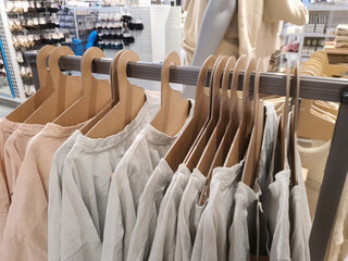 T-shirts hang on eco-friendly cardboard paper hangers on rack in casual clothes store in trendy pastel tones and neutral colors. Selective focus