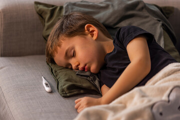 Adorable little child boy sleeping in the bed facing the camera. Young boy is sick at home and...