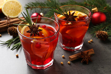 Delicious punch drink with cranberries, orange and spices on grey table
