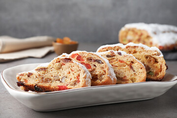 Traditional Christmas Stollen with icing sugar on grey table