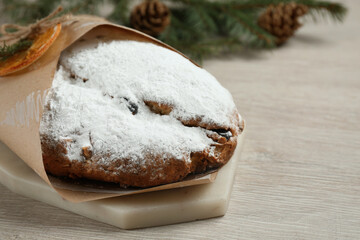 Wrapped Christmas Stollen with decoration on wooden table, closeup