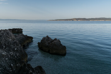 Rocky Adriatic sea shore and Brac island in distance in croatia at summer morning