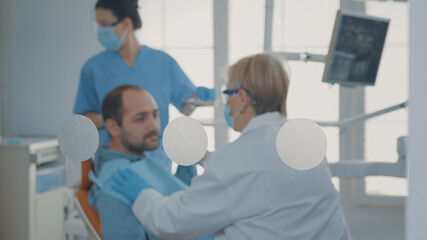 Fototapeta premium Specialist examining patient with denture problems and caries, preparing for dental surgery at oral care clinic. Dentist doing orthodontic consultation and consulting man in pain.