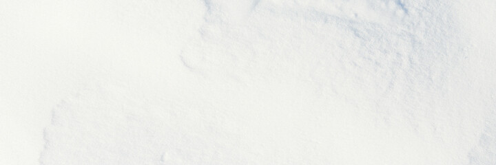 Beautiful winter background with snowy ground. Natural snow texture. Wind sculpted patterns on snow surface. Wide panoramic texture for background and design.
