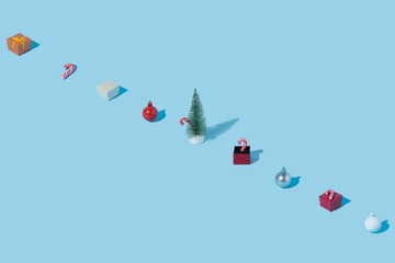 Pattern made of New Year's elements on pastel blue background. Christmas tree, candy cane, surprise box and baubles. Minimalistic aesthetic idea.