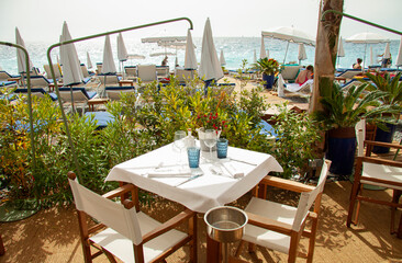 Table and chairs on table with glasses, cutlery and white napkin in a fancy restaurant by the sea.