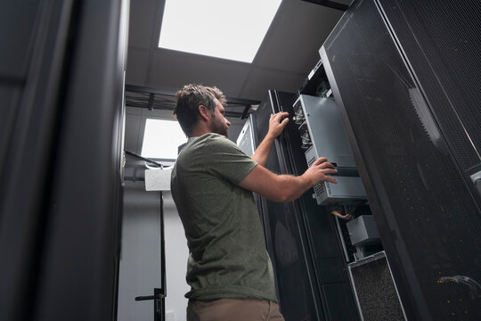IT engineer working In the server room or data center The technician puts in a rack a new server of corporate business mainframe supercomputer or cryptocurrency mining farm. 