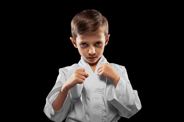 One little kid, boy, taekwondo athlete posing isolated over dark background. Concept of sport, education, skills