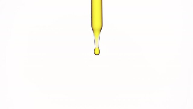 Macro shot of drops of olive oil are falling down from lab dropper on white background | Abstract body care cosmetics with olive oil formulation concept